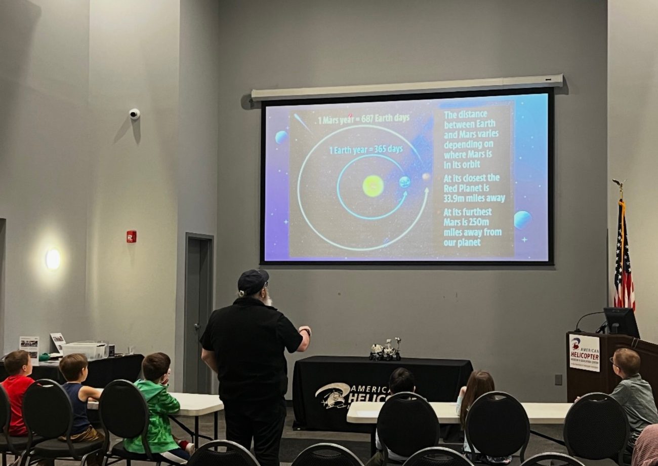 Kids seated at a STEM Spark workshop watching a presentation about Mars and the solar system.